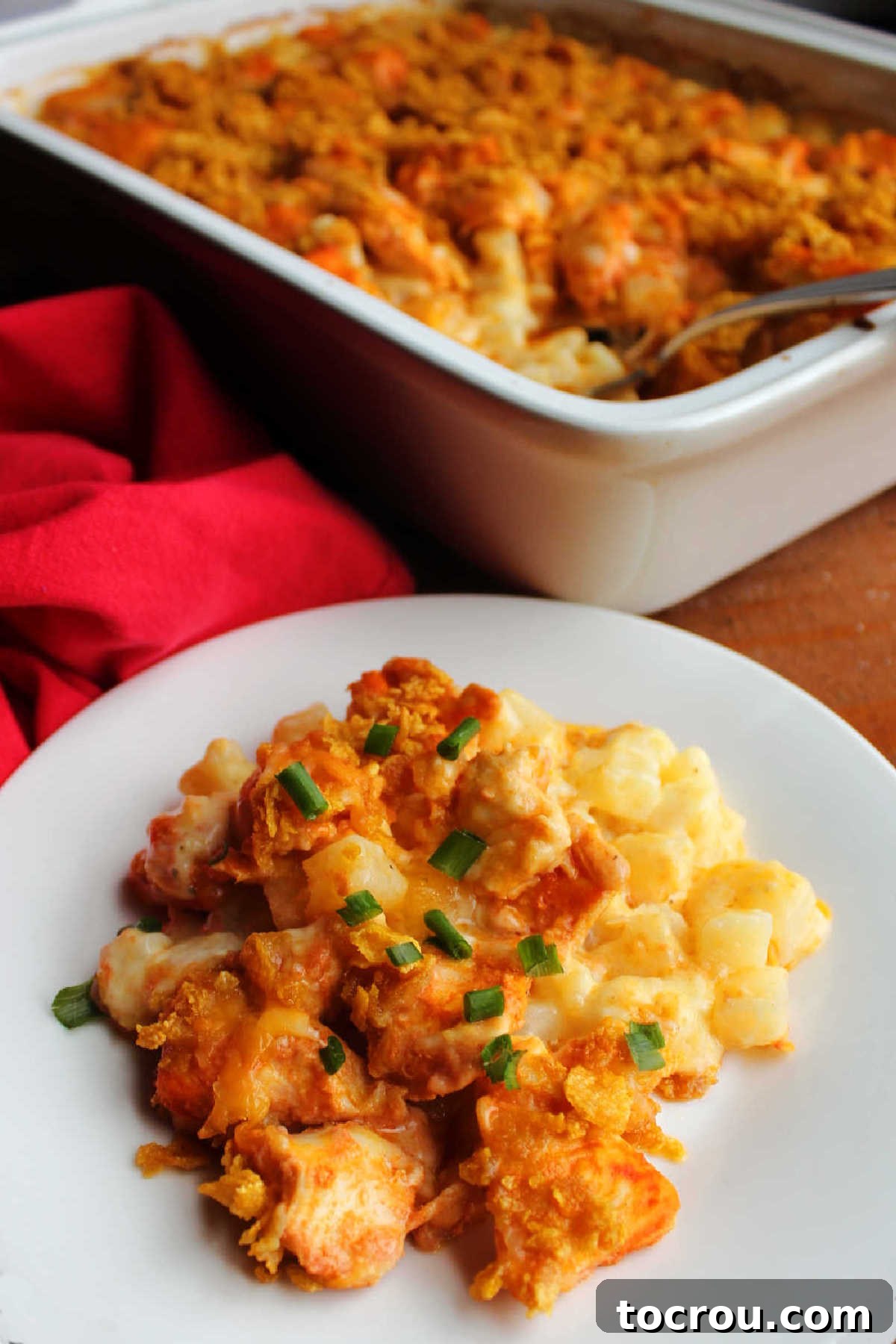 A close-up of a serving of buffalo chicken and cheesy ranch potato casserole, showing the layers of chicken, potatoes, cheese, and crunchy topping, ready to eat.
