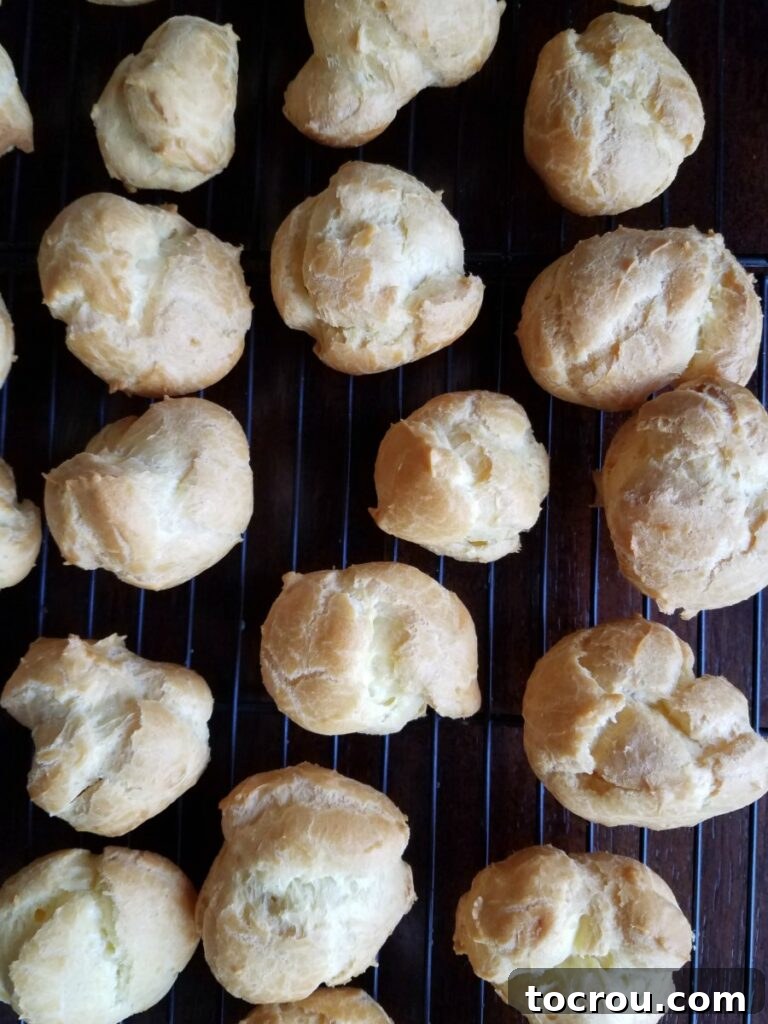 Savory Shrimp Profiterole Bites 6 freshly baked cream puffs cooling on wire rack.