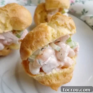 Shrimp salad with creamy dressings and bits of celery inside a golden brown choux pastry profiterole.