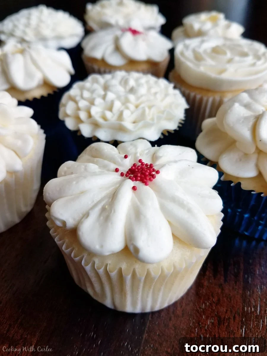 white cupcakes topped with Italian meringue buttercream flower decorations.