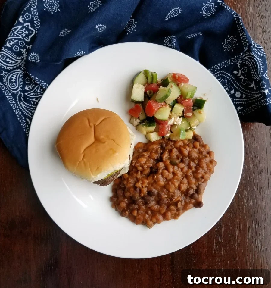 Smoky Slow Cooker Chuckwagon Beans 6 plate with burger, beans and tomato cucumber salad.