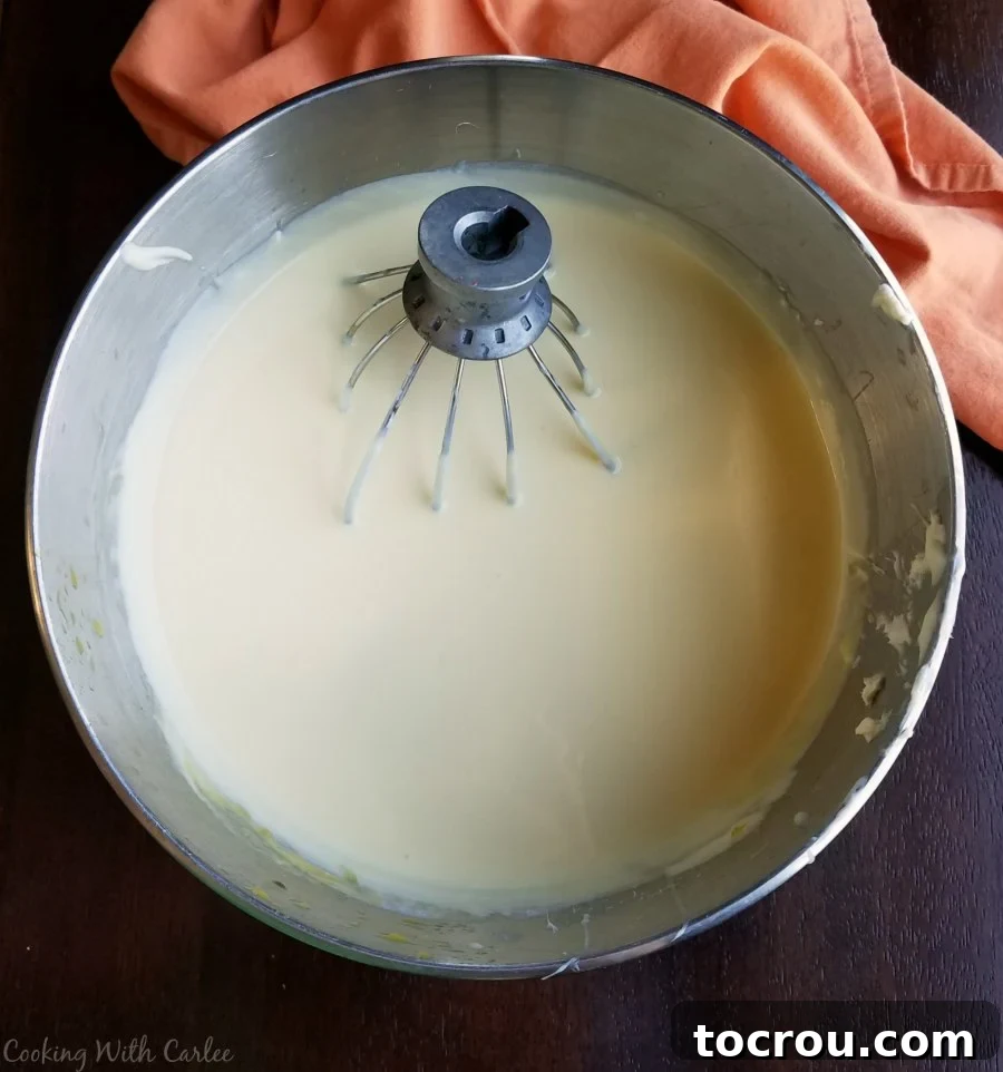Mixer bowl filled with the vibrant orange cream cheese ice cream base, ready for churning.