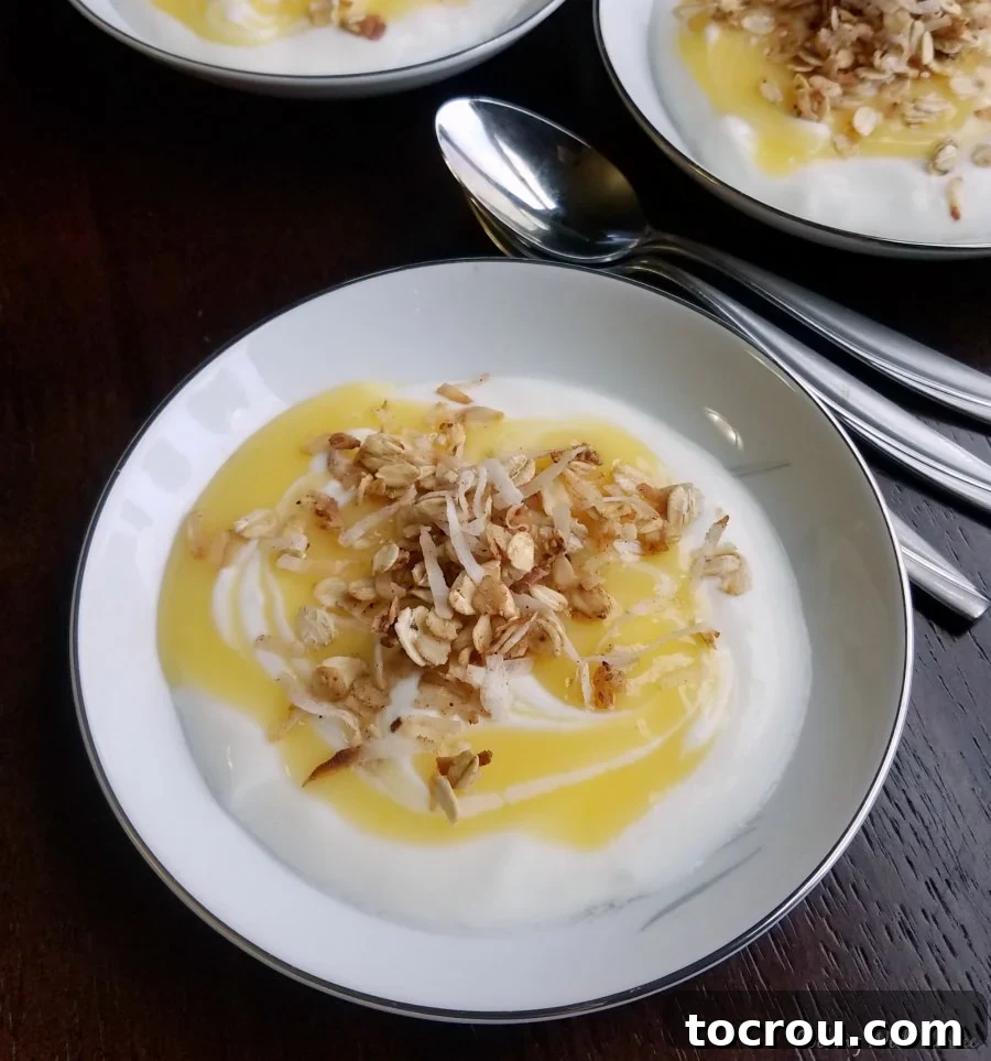 Microwave Lemon Curd Bowl of yogurt topped with a swirl of homemade lemon curd and granola next to spoons, ready to eat.