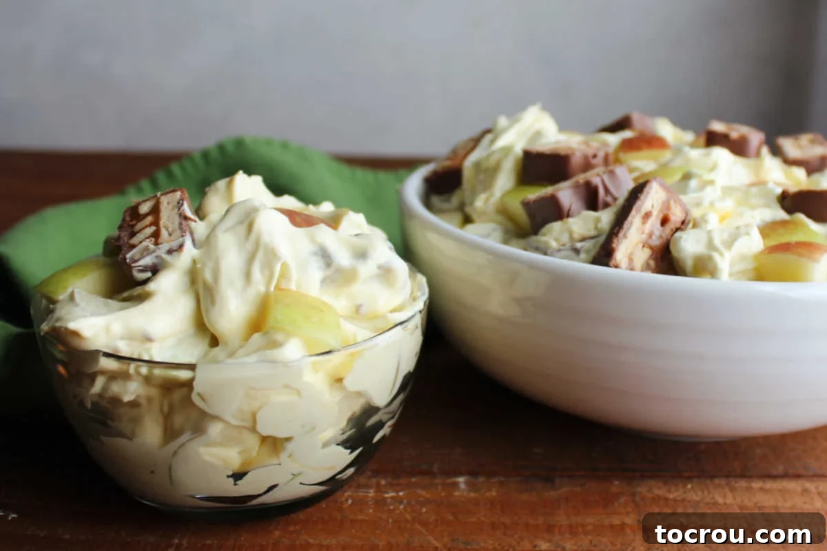 Decadent Apple Snickers Dessert 2 Small bowl of apple salad with snickers and fluffy vanilla pudding dressing next to serving bowl with more snickers salad inside.