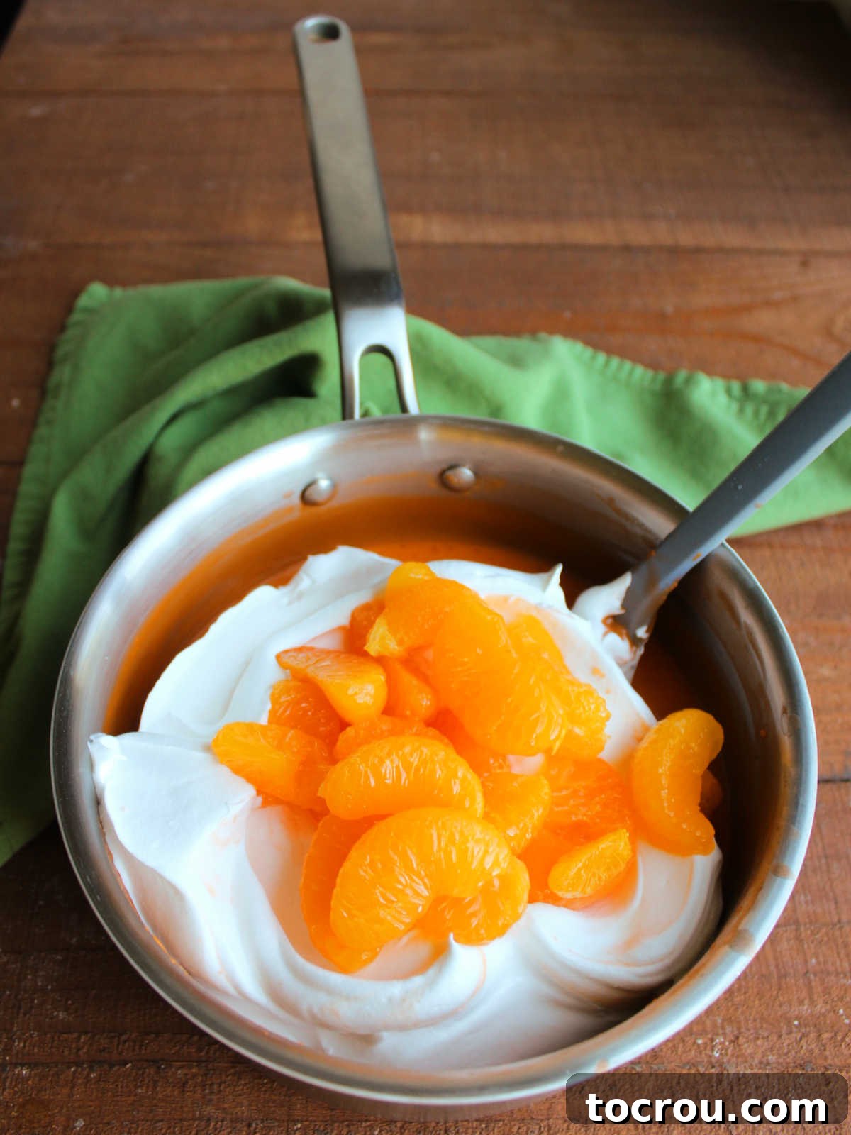 Stirring cool whip and mandarin oranges into cooled pudding and jello mixture. 