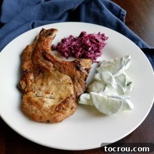 Dinner plate with honey mustard grilled bone in pork chop, creamy cucumber salad, and shaved beet salad.