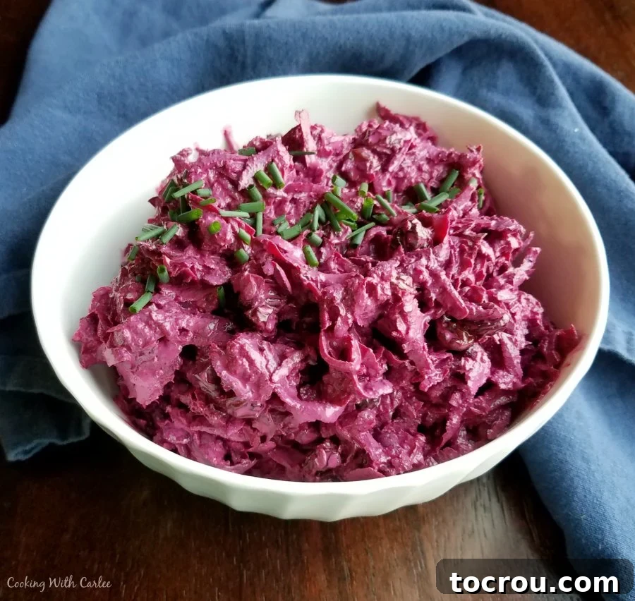 A bowl of creamy Russian beet salad, garnished with fresh chives, showcasing its rich, deep red color.