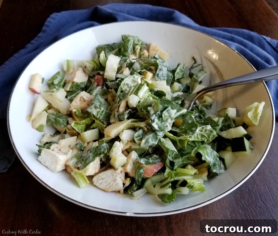 A close-up of a bowl of bok choy salad, thoroughly tossed in its creamy dressing, showcasing every ingredient coated in the delicious sauce.
