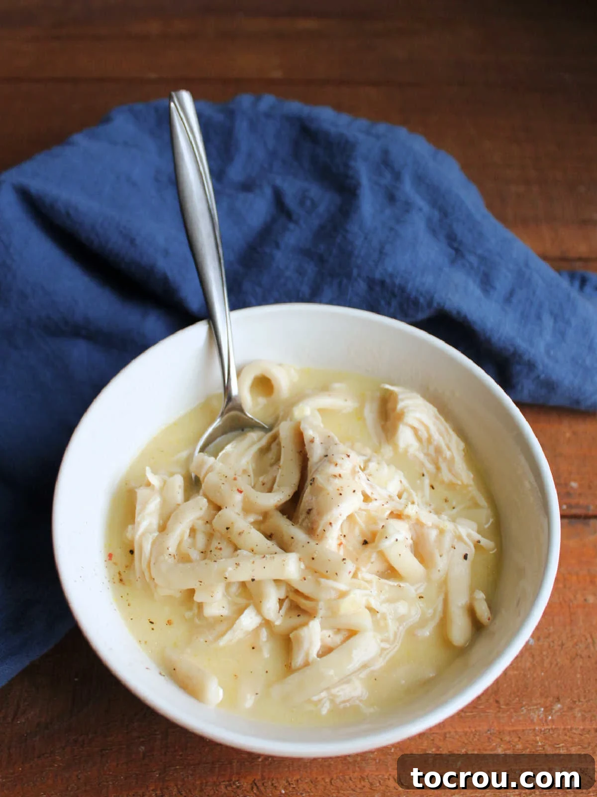 Bowl of creamy chicken and noodle soup with spoon, ready to eat. 