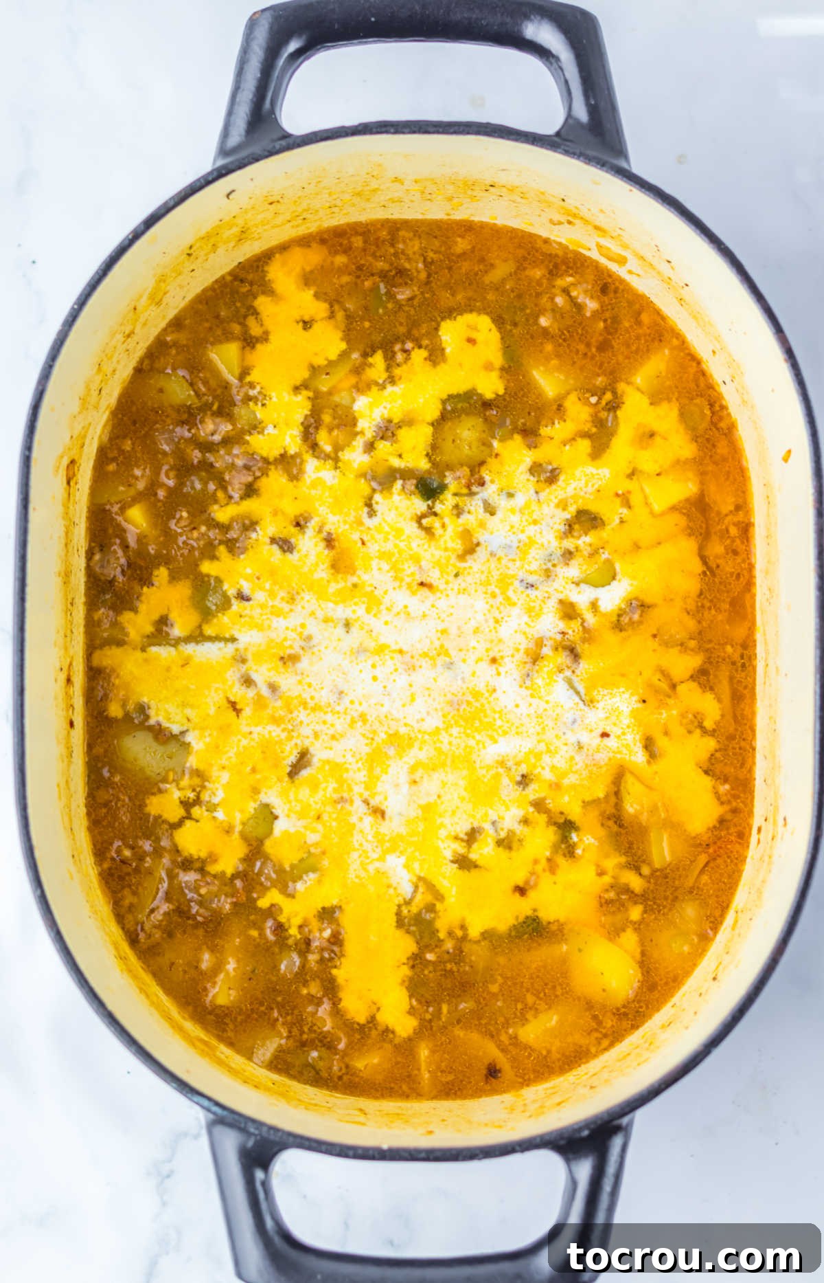 Adding Heavy Cream Heavy cream poured into the cooked Italian sausage and potato chowder, ready to be stirred in for a rich, creamy finish.