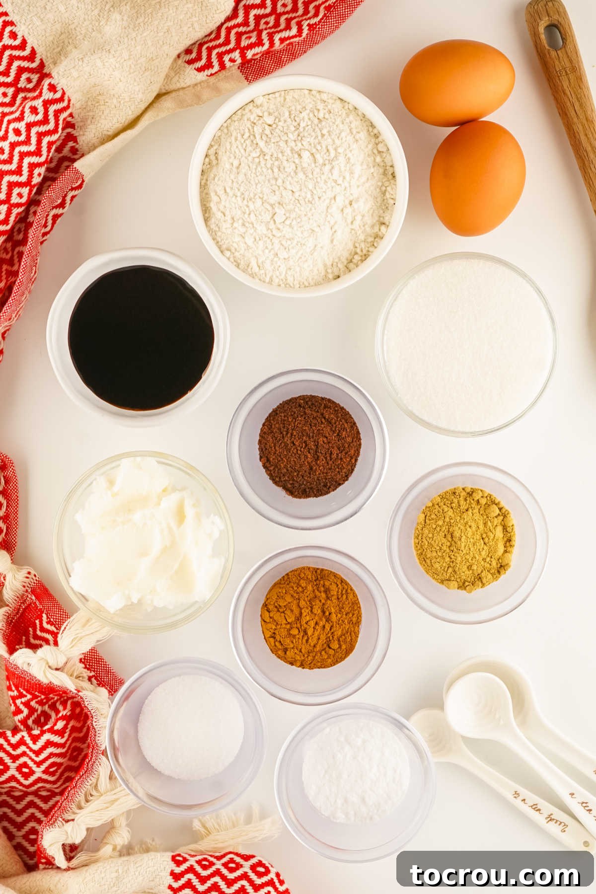Ingredients including flour, shortening, molasses, eggs, sugar, cinnamon, cloves, and ginger ready to be made into ice box gingersnaps.