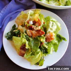 small plate piled high with wilted lettuce salad with big chunks of bacon and hard boiled egg mixed in.