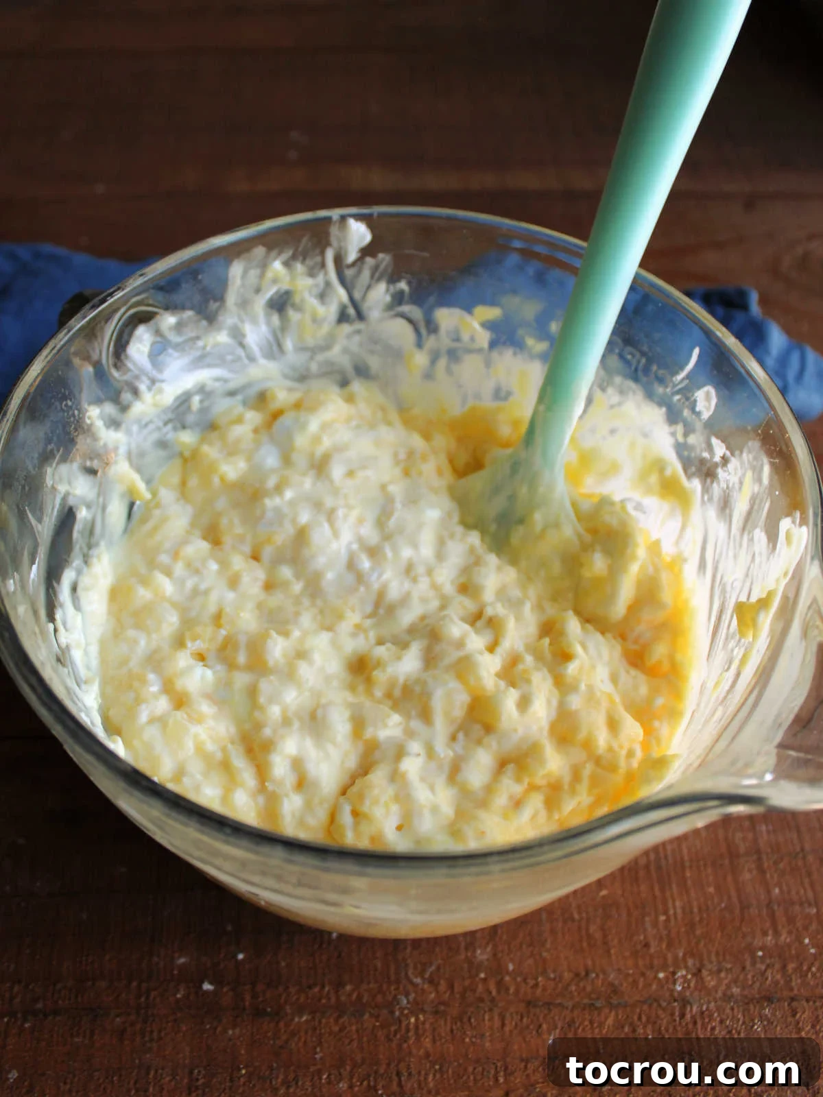 A mixing bowl displaying the creamy pineapple and pudding mixture after whipped topping has been gently folded in.