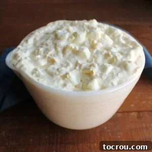 Vintage bowl filled with pineapple fluff featuring crushed pineapple and mini marshmallows in creamy vanilla pudding mixture.