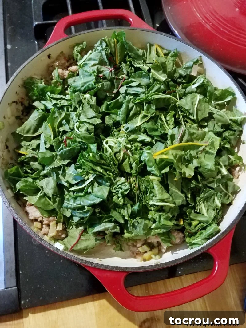 A large pot filled with a generous amount of chopped chard, ready to be cooked down.