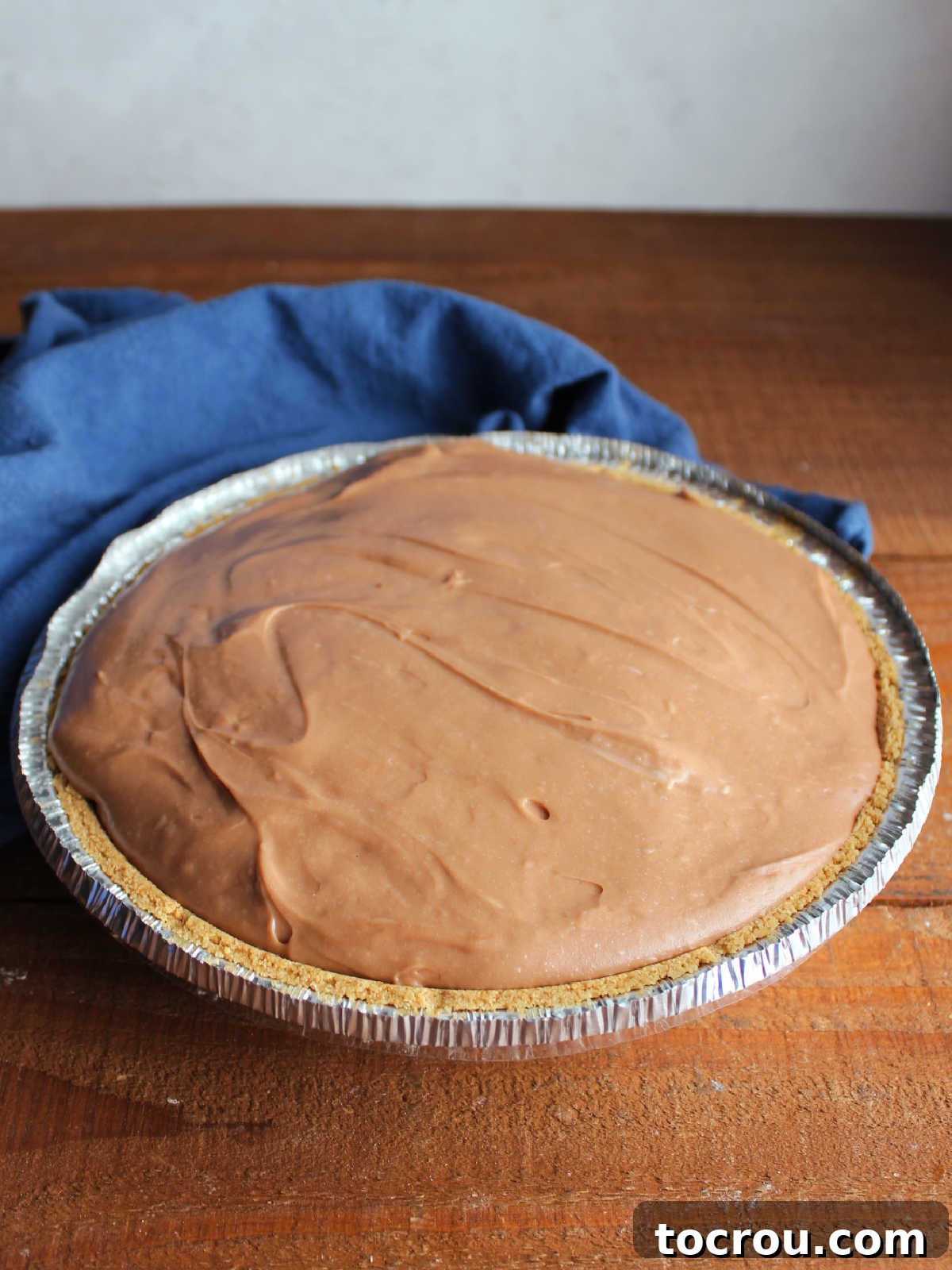 A beautifully crafted whole chocolate no-bake cheesecake pie, resting in its sturdy graham cracker crust. The smooth, creamy chocolate and cream cheese filling is perfectly set, ready to be sliced and enjoyed, showcasing its irresistible appeal.
