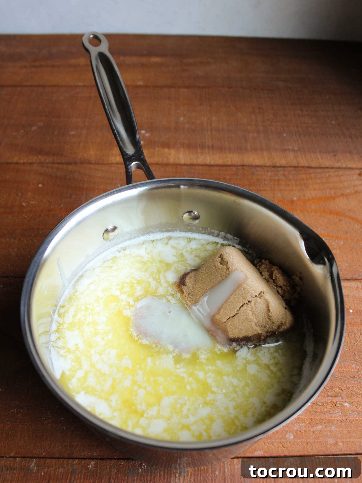 Melted butter, corn syrup, brown sugar, and sweetened condensed milk in saucepan, ready to be made into caramel. 