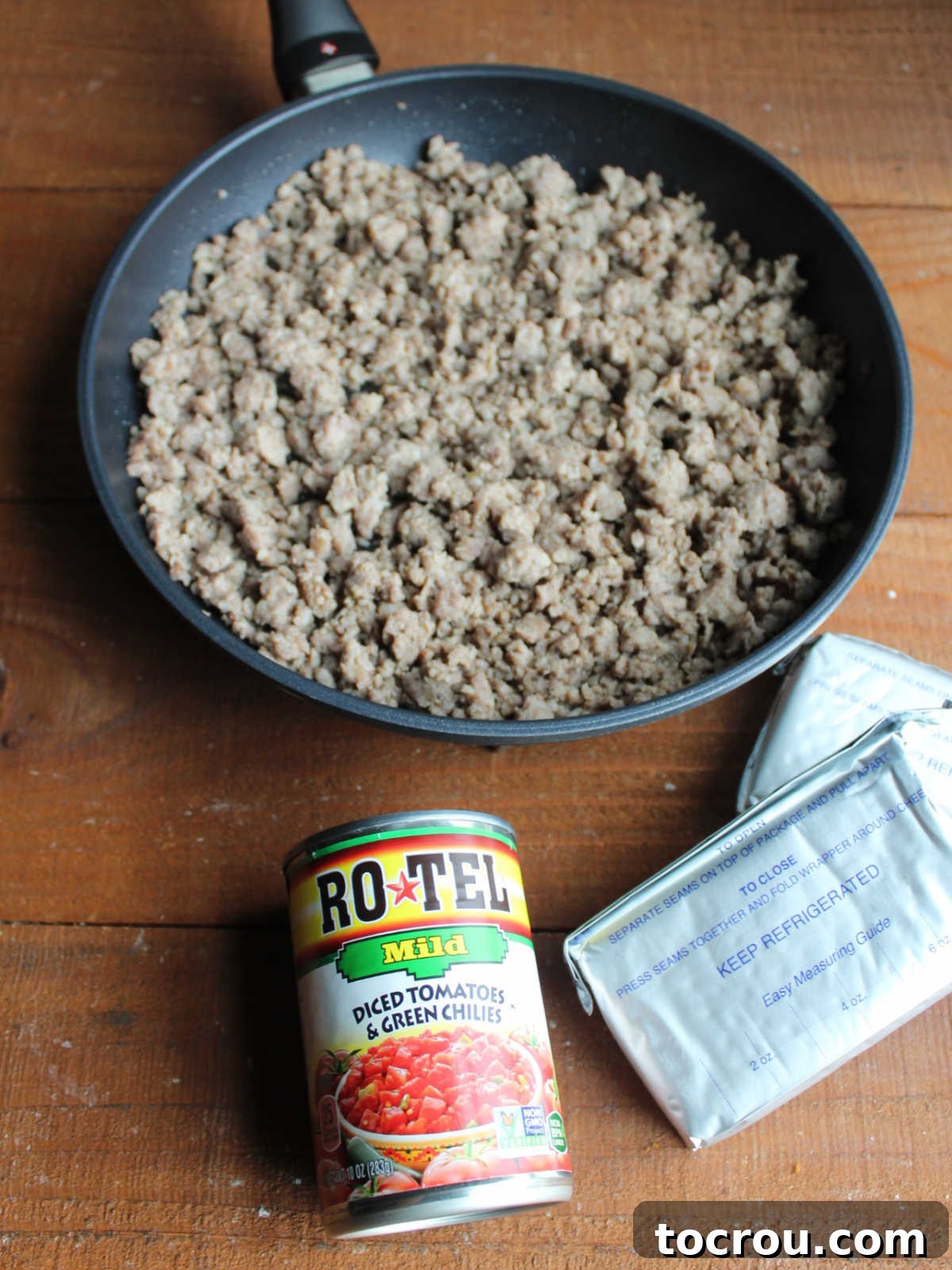 Ingredients including browned sausage, Rotel, and cream cheese ready to be made into a dip.