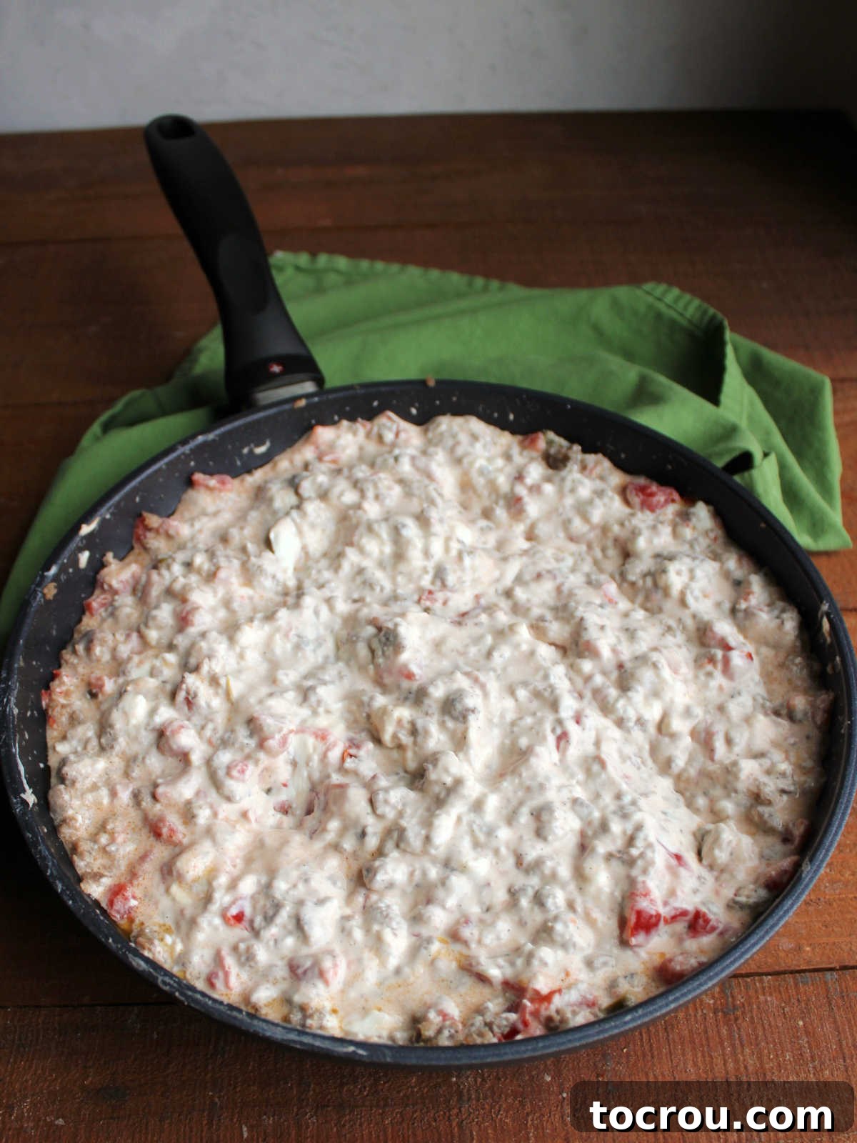 Skillet filled with creamy sausage dip with rotel after the cream cheese has been melted.