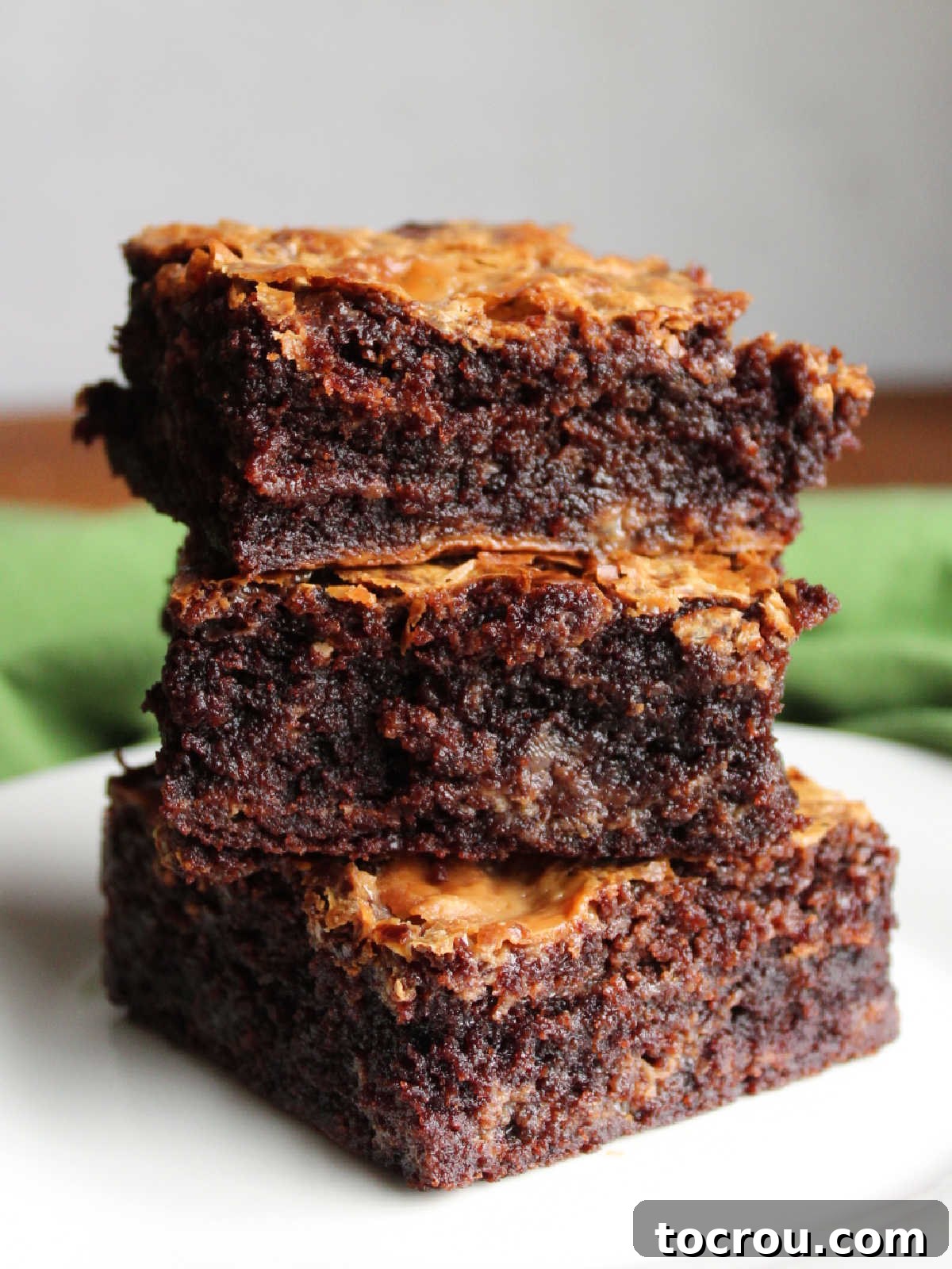 Stack of box brownie mix with condensed milk brownies showing how thick and fudgy they are with a bit of caramelized goodness throughout.