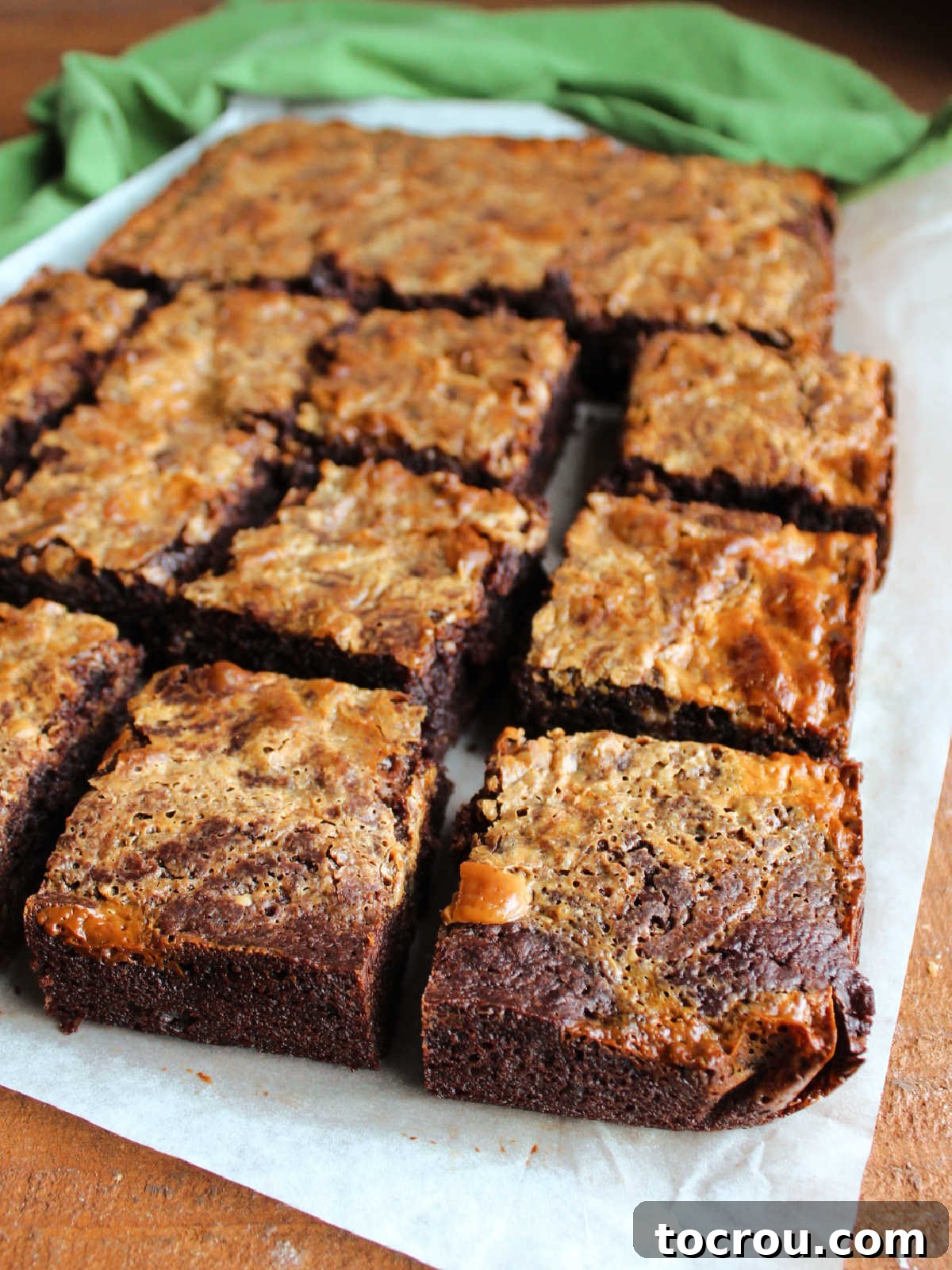Baked and cooled brownies cut into squares showing the crackled tops and how the sweetened condensed milk took on a golden caramel color.