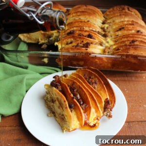 Pouring maple syrup over a slice of breakfast casserole with pancakes with crumbled sausage between the layers baked in an egg mixture.