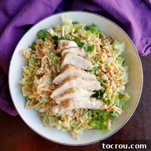 Bowl of napa salad with toasted ramen and chicken breasts.
