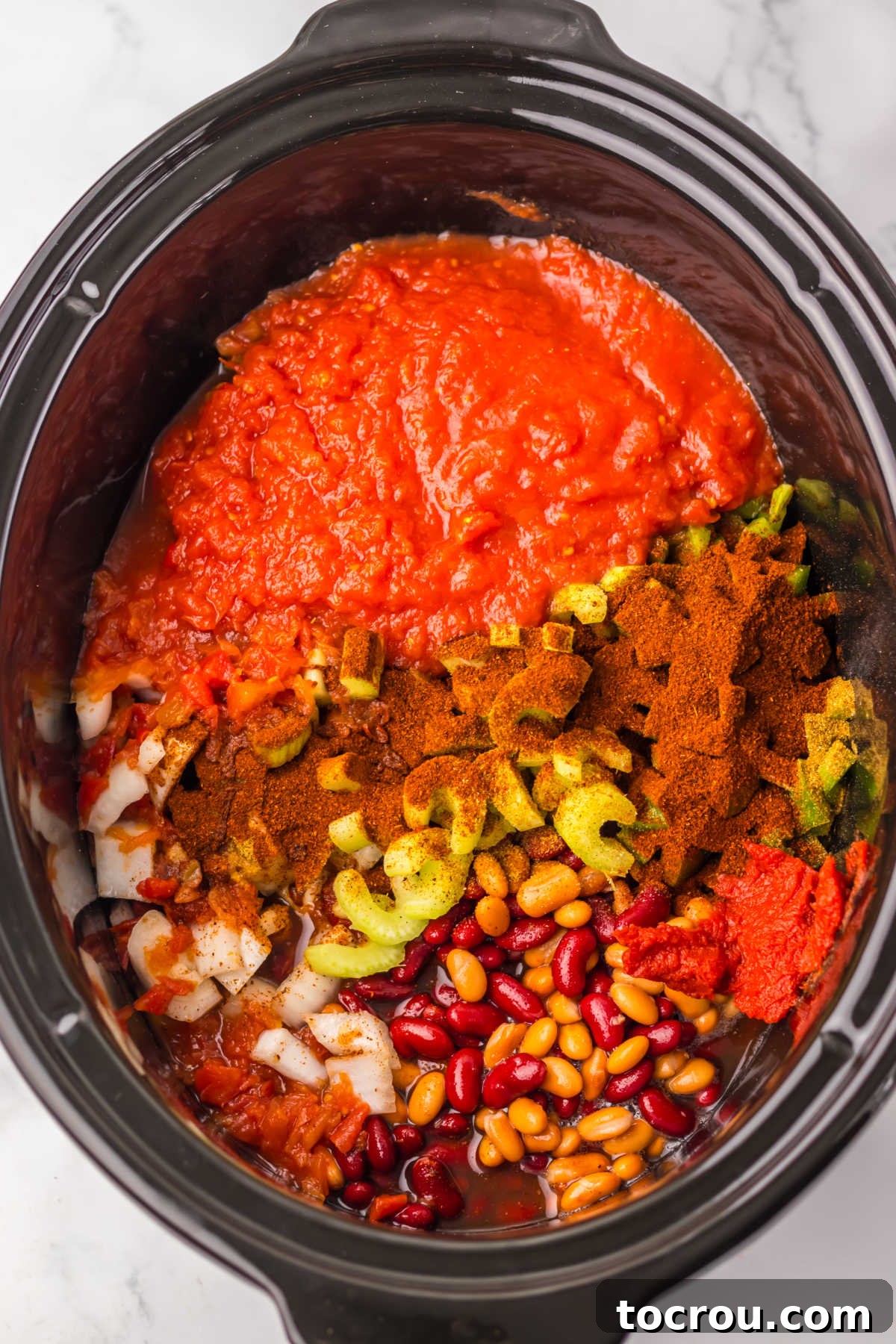 Chili ingredients added to the crockpot, showing a mix of colors and textures before cooking.