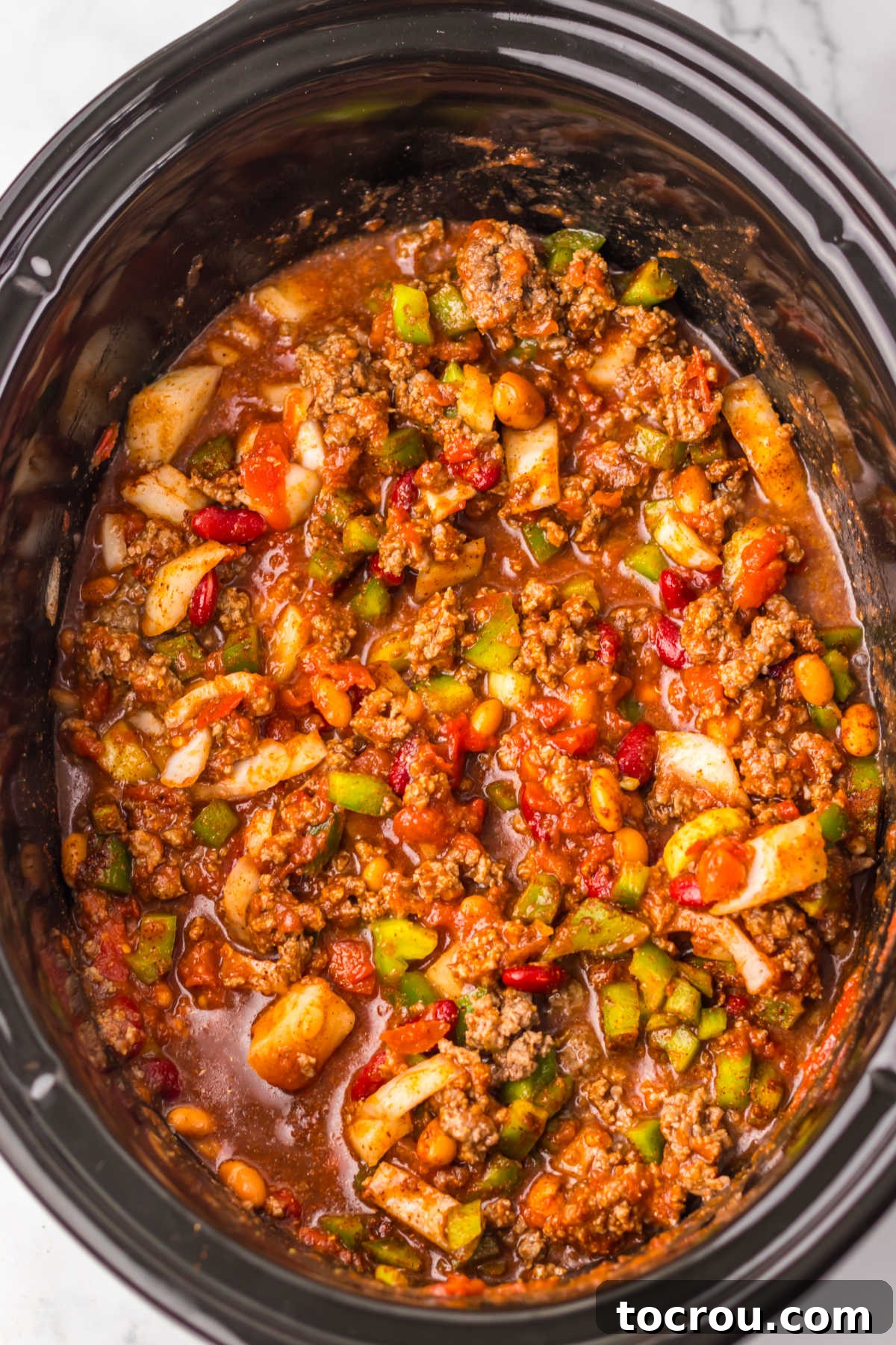Crockpot filled with all the chili ingredients after being stirred together, prior to cooking.