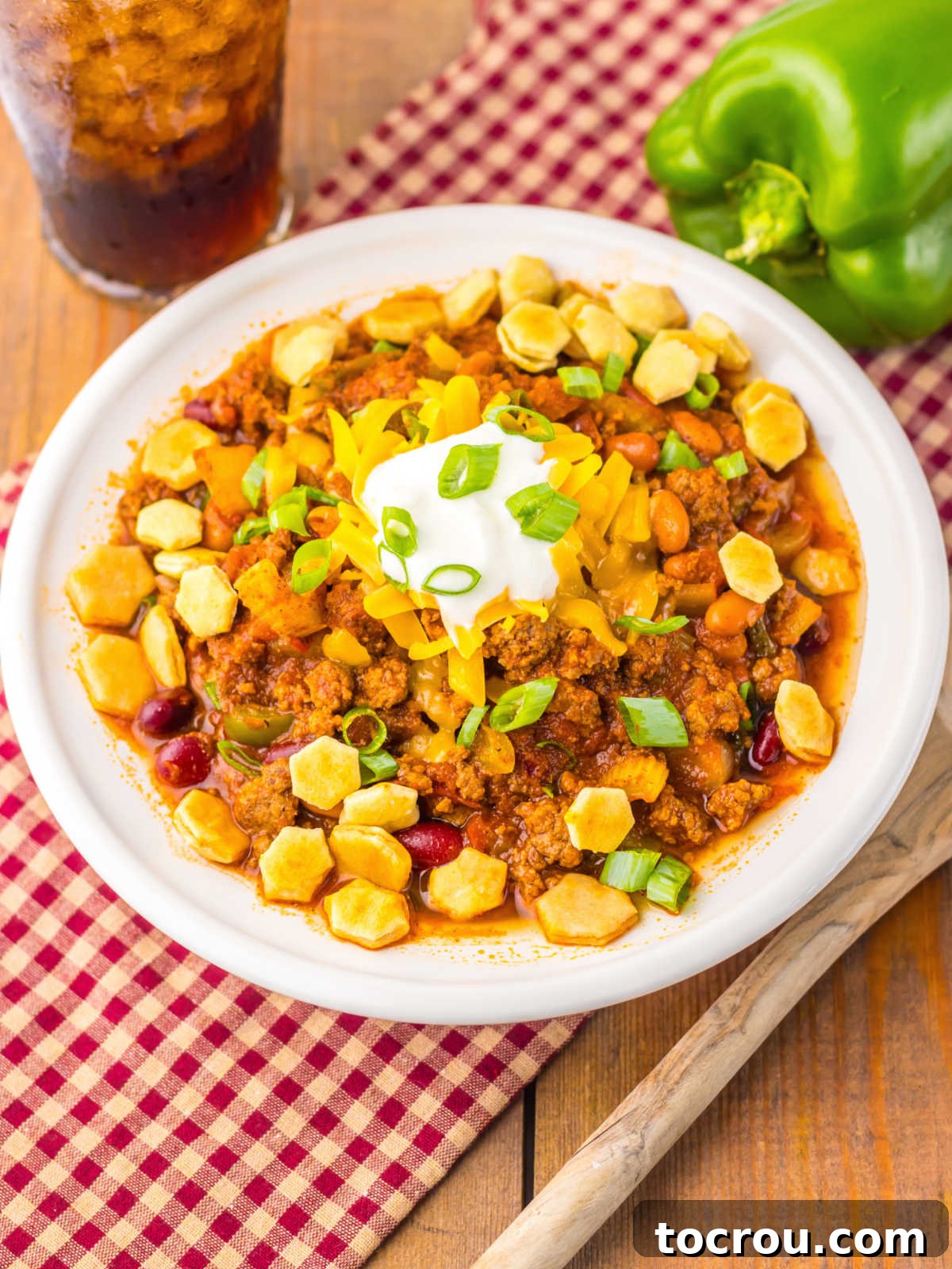 Bowl of homemade Wendy's style chili, generously topped with soup crackers, shredded cheese, and a dollop of sour cream.