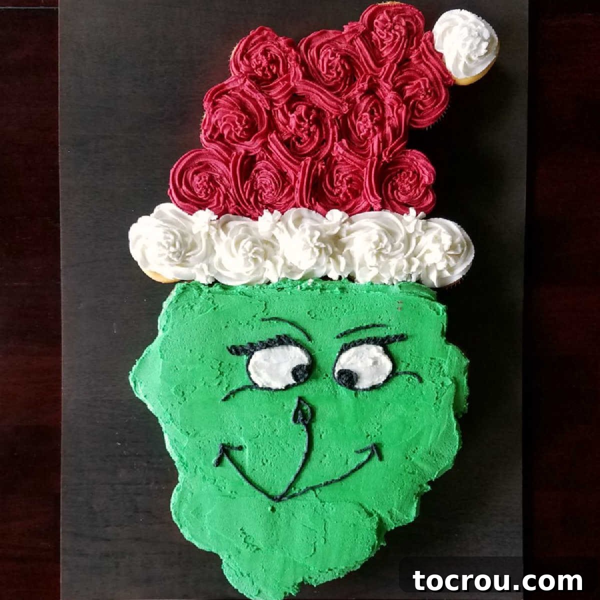 Grinch pull-apart cupcake cake adorned with a festive Santa hat, ready for a Dr. Seuss themed party.