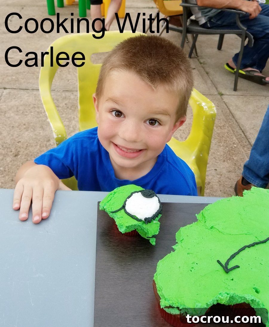 Little boy enthusiastically eating a cupcake with the Grinch's eyeball on it from the pull-apart cake.