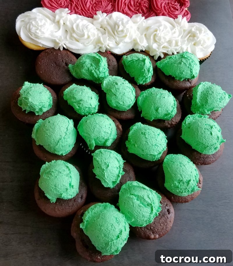 Scoops of vibrant green frosting placed on chocolate cupcakes, ready to be smoothed out to form the Grinch's face.