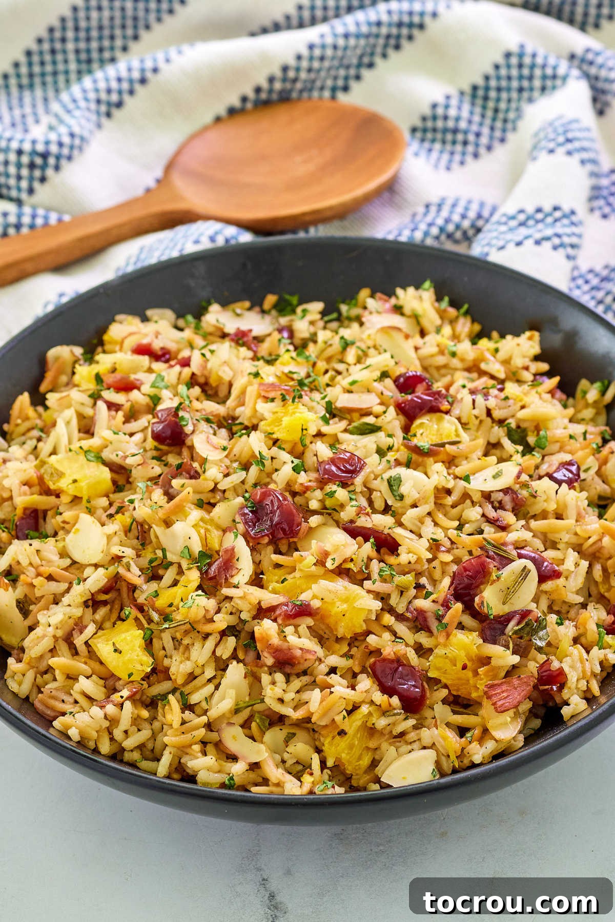 Individual Serving of Rice Pilaf Close-up shot of a small serving bowl filled with Cranberry Orange Rice Pilaf, highlighting the distinct grains of rice, bright red cranberries, orange zest, slivered almonds, and green herbs.