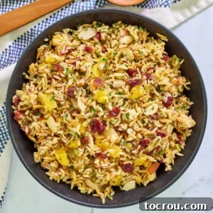 Serving bowl filled with cranberry orange rice pilaf with fresh herbs, almonds, toasted orzo, and rice.