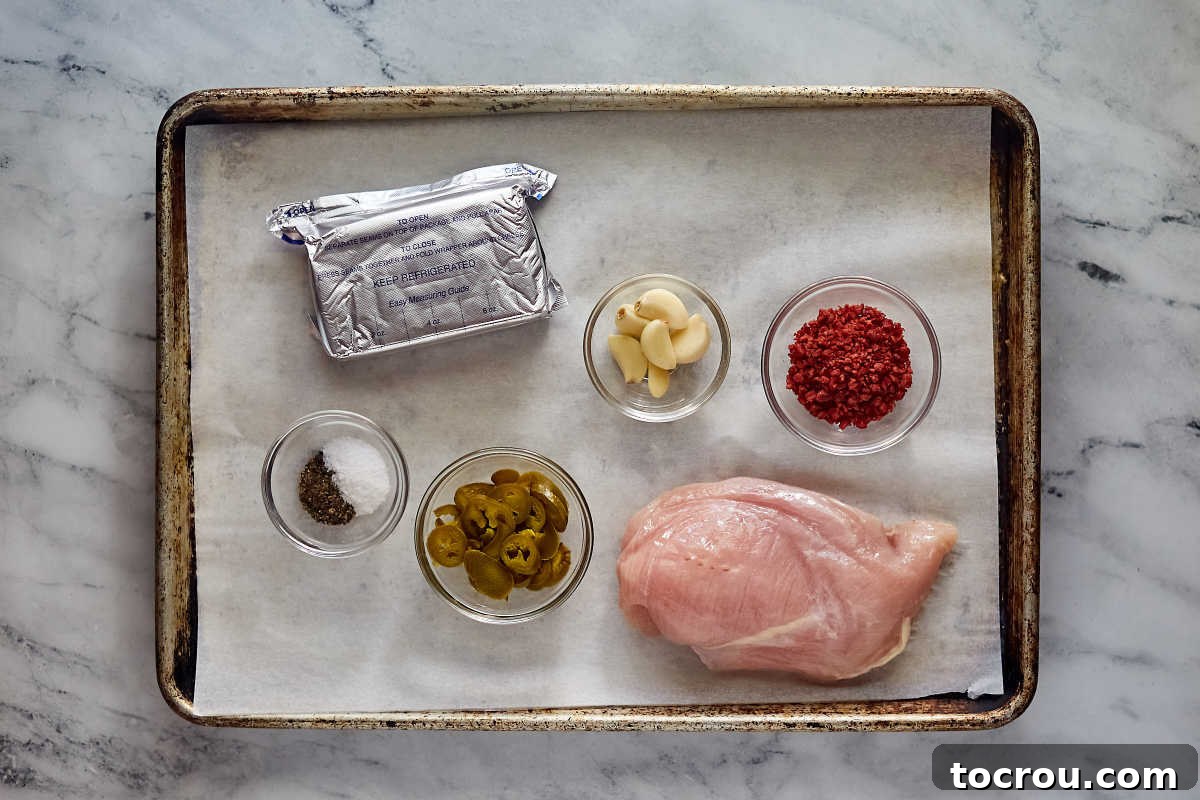 Creamy Jalapeno Popper Chicken 3 Ingredients including chicken breasts, crumbled bacon, garlic, pickled jalapenos, salt, pepper, and cream cheese, ready to be made into cheesy jalapeno stuffed chicken.