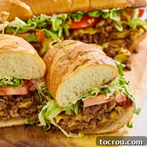 Close chopped cheese sandwich with ground beef and american cheese mixture on hoagie roll with tomato, lettuce, and mayonnaise.