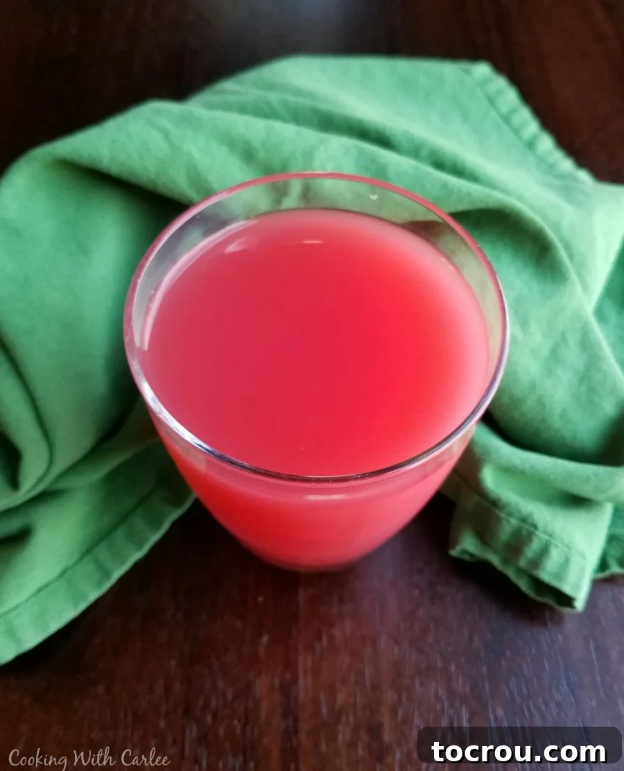 An overhead view of a glass brimming with frothy pink sherbet punch, invitingly ready to drink.