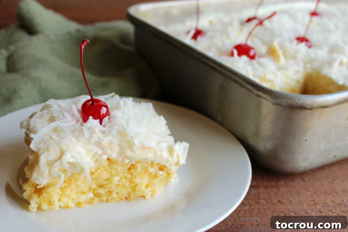Ambrosia Poke Cake Slice A delectable slice of Ambrosia Poke Cake, showcasing its moist orange cake base, rich condensed milk soak, and fluffy pineapple, coconut, and cherry topping, rests on a plate beside the remaining cake in its pan.
