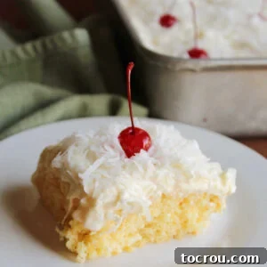 A delicious piece of Ambrosia Poke Cake, featuring its moist orange cake base, infused with an orange condensed milk soak, crowned with fluffy pineapple and vanilla frosting, shredded coconut, and a maraschino cherry.