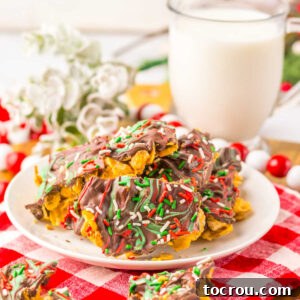 Plate of cornflake brittle with chocolate layer topped with red and green candy melt swirls and sprinkles for Christmas.