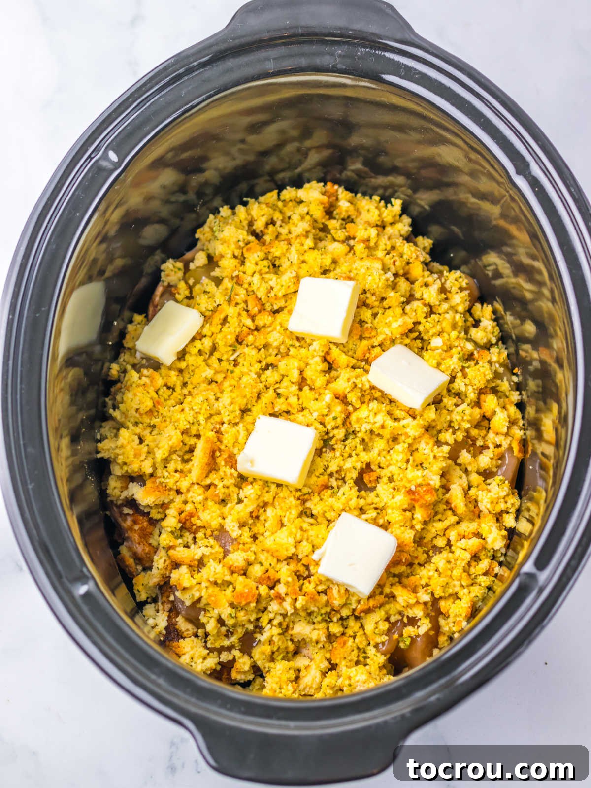 Stuffing mix over the top of the apple pie filling with pats of butter on top, ready to cook. 