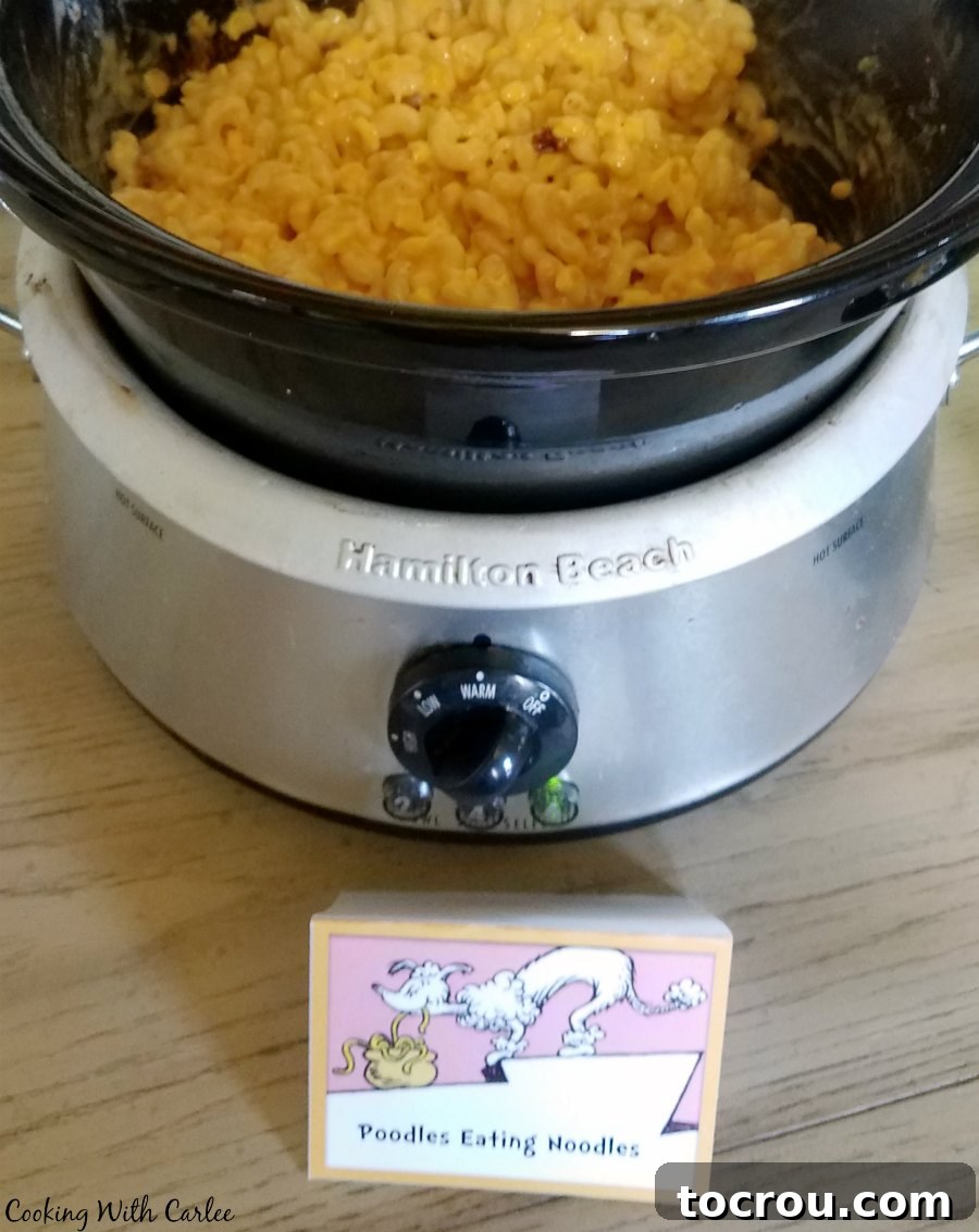 Poodles with Noodles Mac and Cheese Slow cooker filled with creamy macaroni and cheese with corn, adorned with a 'Poodles with Noodles' sign.