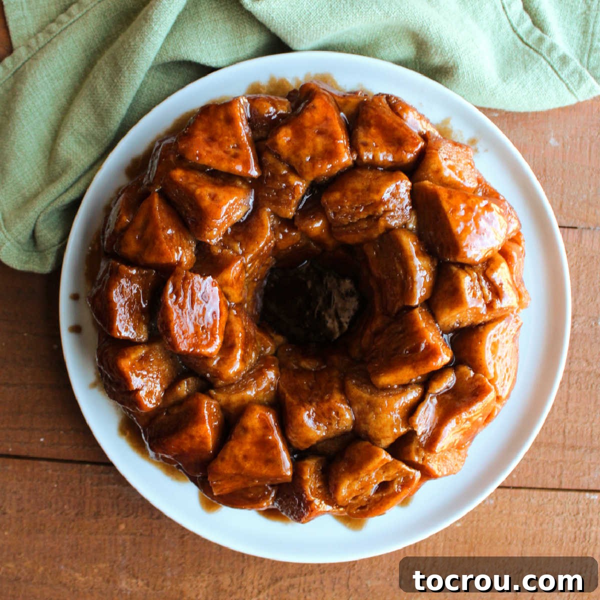 Plate of freshly baked monkey bread with cinnamon sugar coated bits of biscuit in a sticky brown sugar glaze.