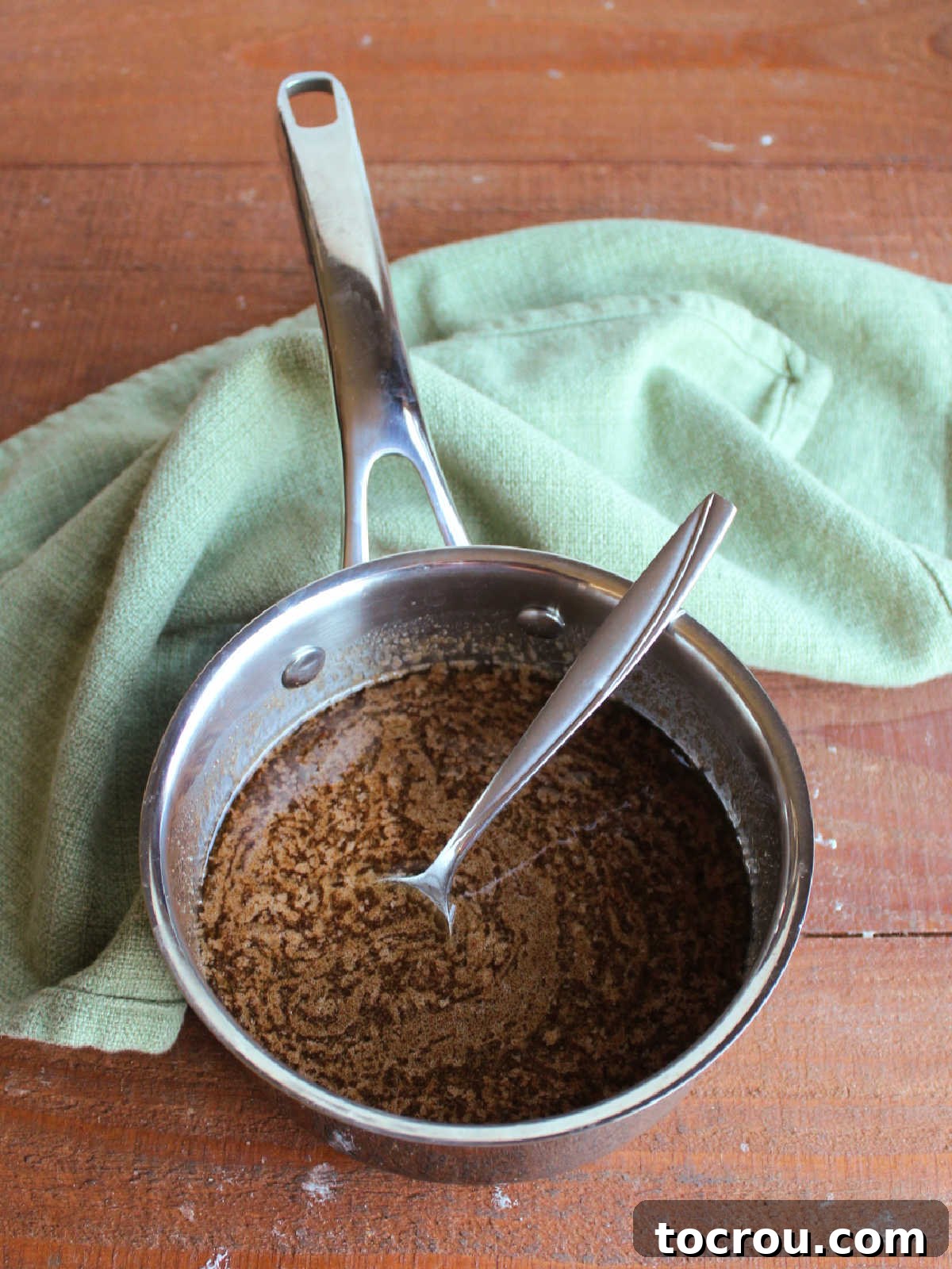 Saucepan with cinnamon, brown sugar, and butter mixture after it has come to a light boil, ready to be poured over biscuits. 