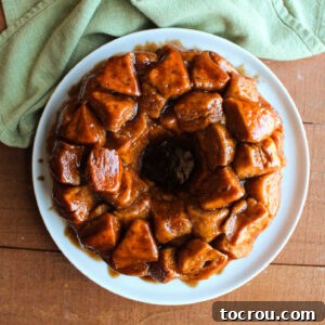 Plate of freshly baked monkey bread with cinnamon sugar coated bits of biscuit in a sticky brown sugar glaze.