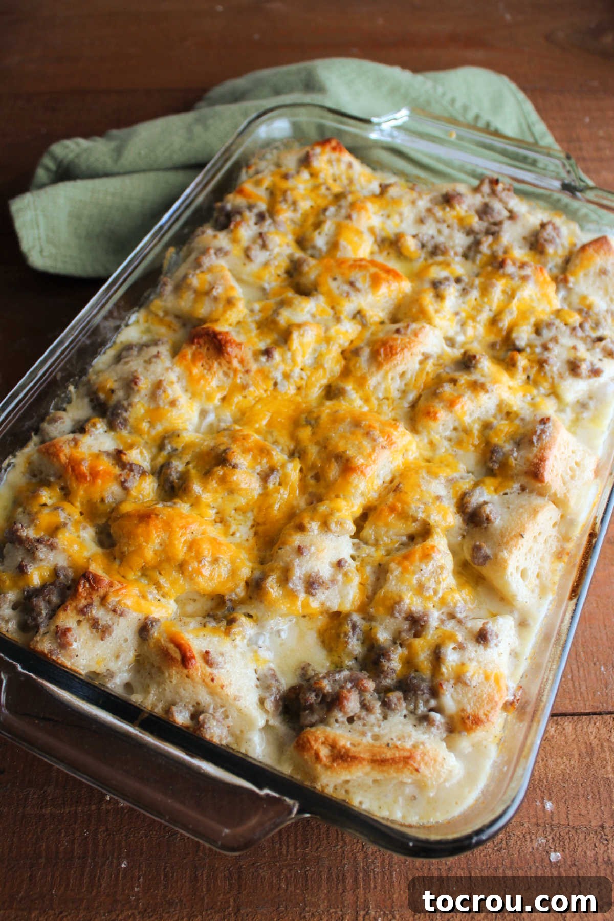 Baked Biscuits and Gravy Bubble Up Freshly baked biscuit and gravy casserole in a dish, showcasing perfectly puffed-up biscuits, thickened bubbly gravy, and a golden-brown melted cheese topping, with delicious crispy edges.