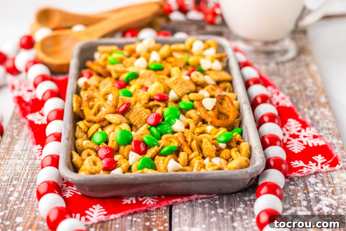 A festive tray of golden maple cinnamon Chex mix, adorned with vibrant red and green Christmas M&Ms and creamy white chocolate chips, freshly made in a slow cooker.
