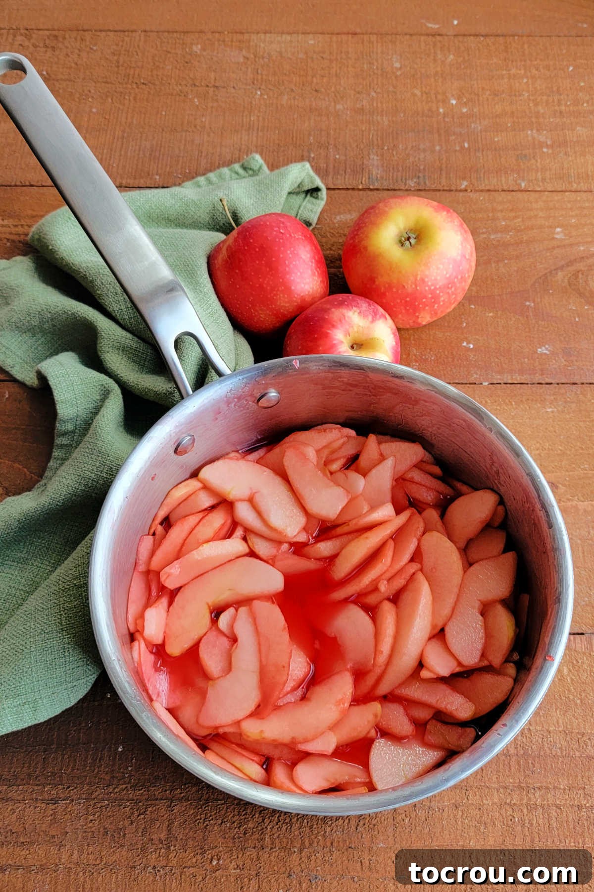 Sliced apples cooked in the red hot, water, and sugar syrup mixture.