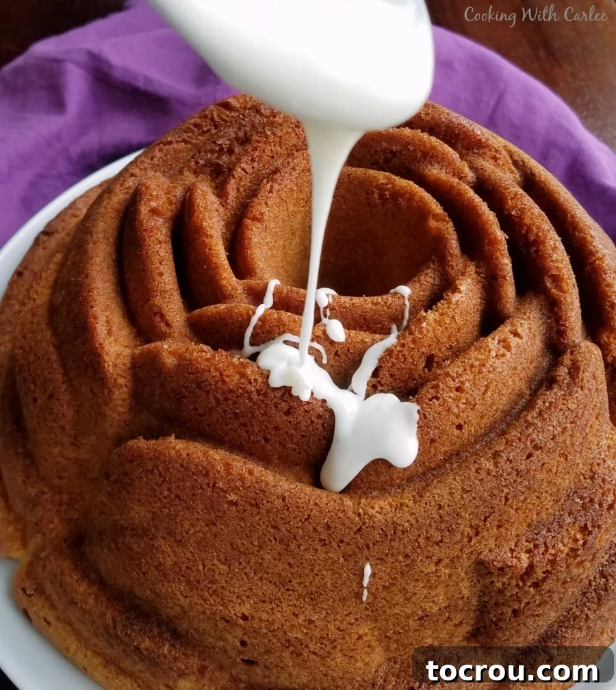 Glazing a Rose Shaped Cake A hand drizzling a smooth white icing over a rose-shaped Vintage Gold Cake, creating an elegant finish.